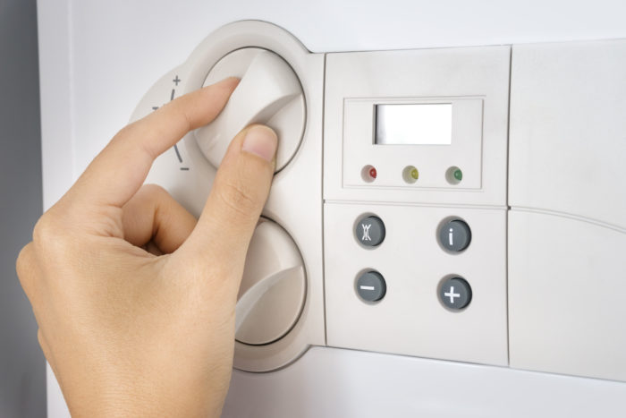 Hand turning heating control dial on combi boiler