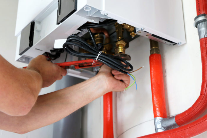 An engineer installing pipework to a standard boiler